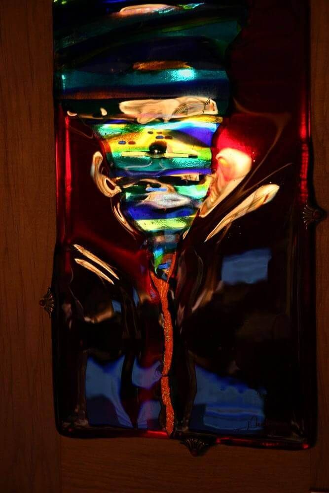 Vitrail abstrait, panneau vertical aux couleurs tourbillonnantes : bleu, rouge, jaune et vert. Encadré dans un cadre en bois.