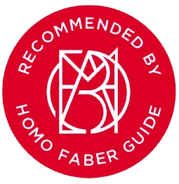 Cercle rouge avec le texte « RECOMMANDÉ PAR LE GUIDE HOMO FABER » et un logo géométrique.