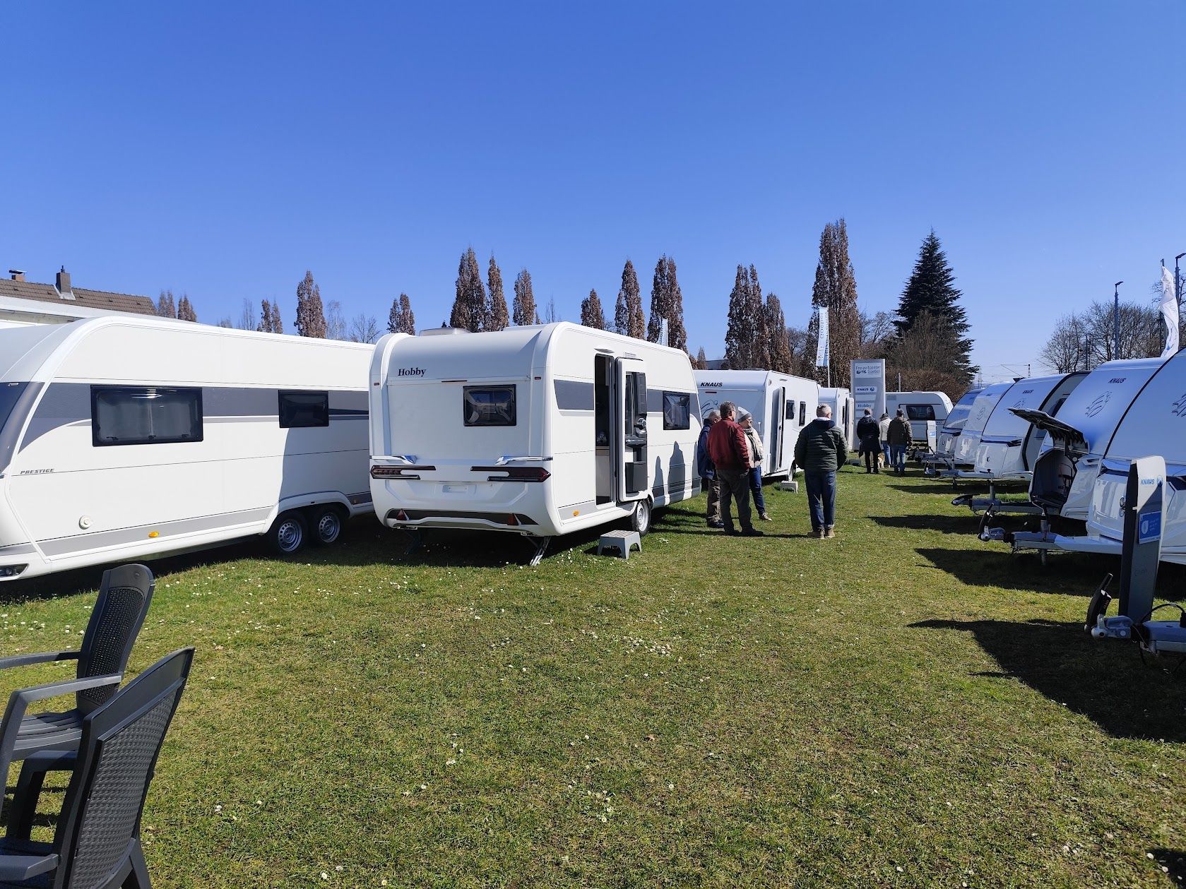 Ein silbernes Auto steht mit einem Wohnwagen am Meer.