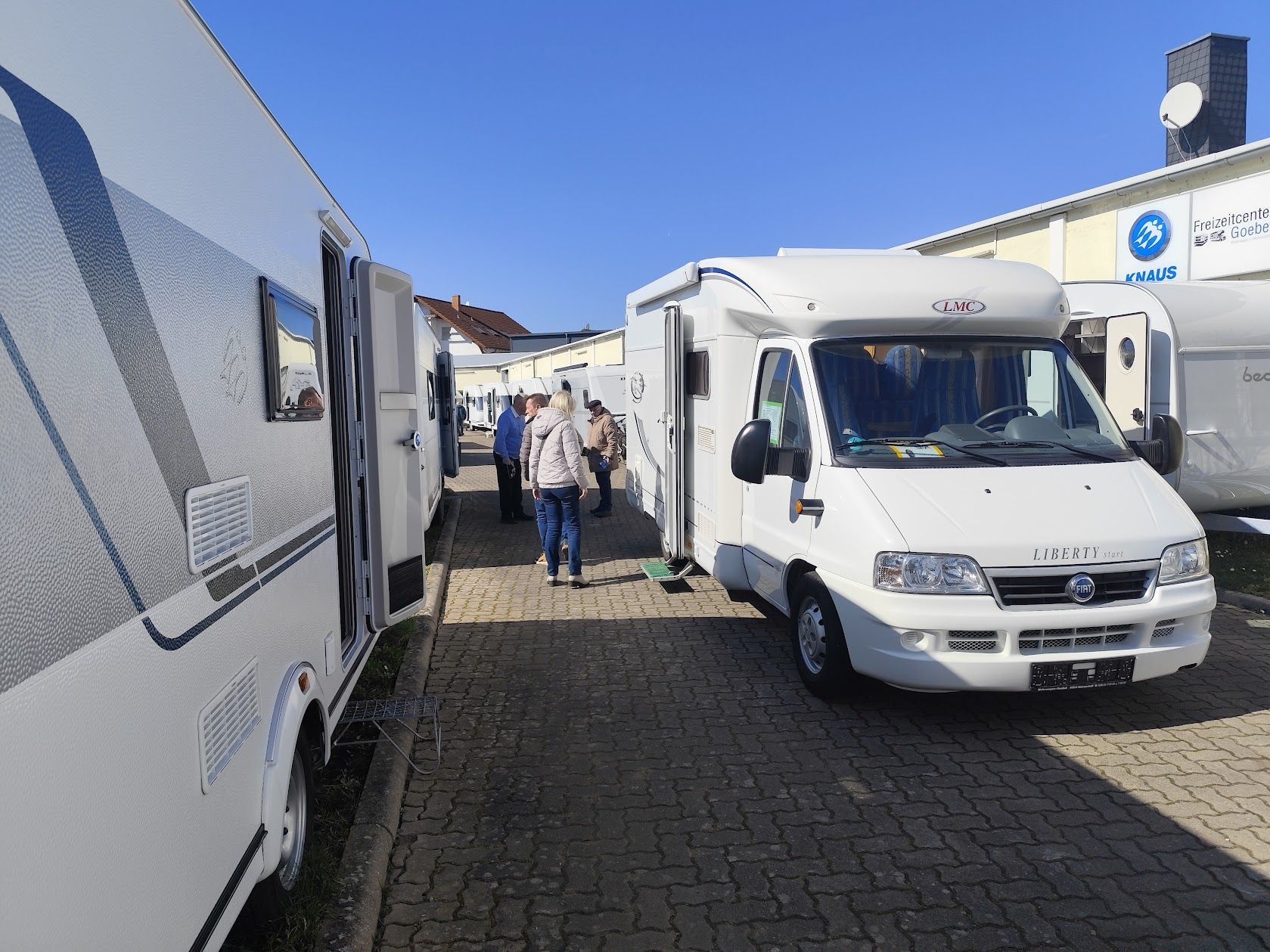 Mehrere verschiedene Wohnmobile stehen am Ufer eines Sees