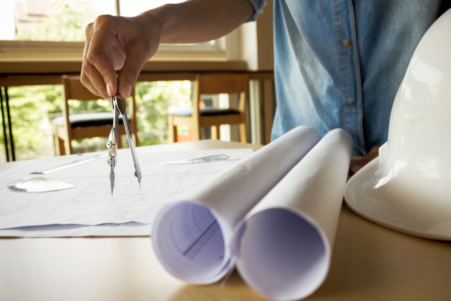 Ferramentas de arquitetura em plantas, tablet exibindo esboço do projeto de um banheiro.
