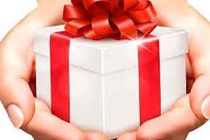 Una persona sostiene una caja de regalo blanca con una cinta y un lazo rojos.