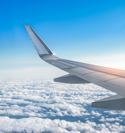 Aile d’avion au-dessus des nuages sous un ciel bleu éclatant.