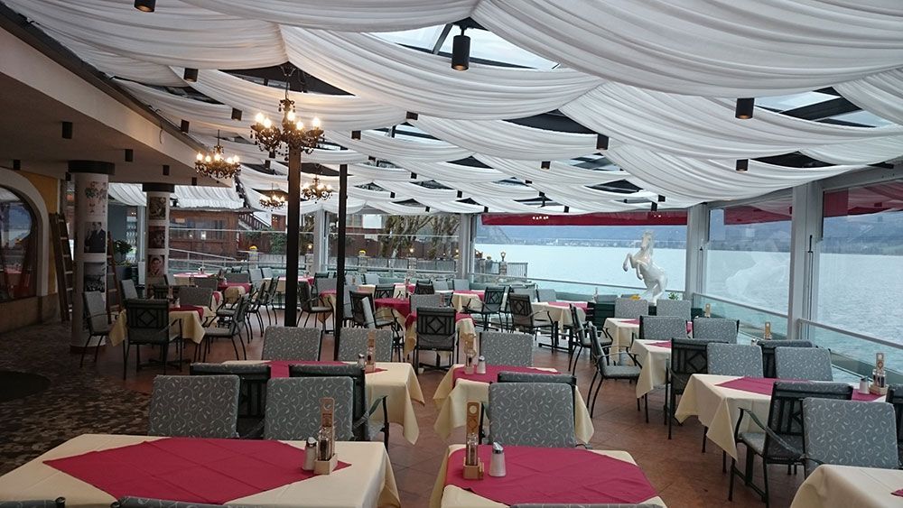 Ein Restaurant mit Tischen und Stühlen und Blick aufs Wasser.