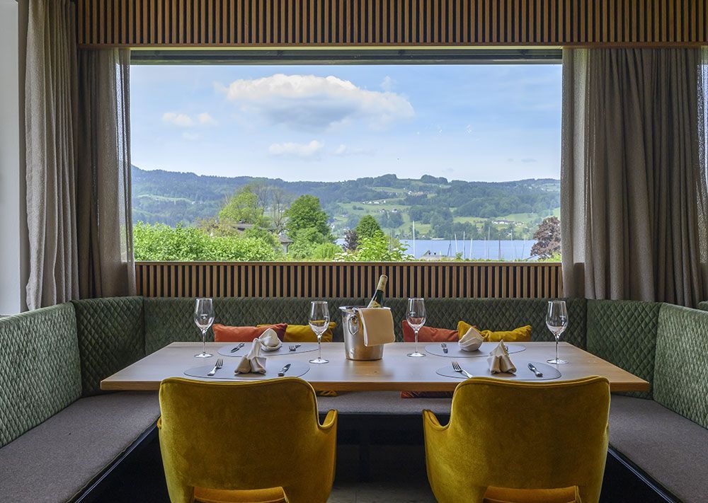 Ein Tisch und Stühle vor einem großen Fenster mit Blick auf einen See.