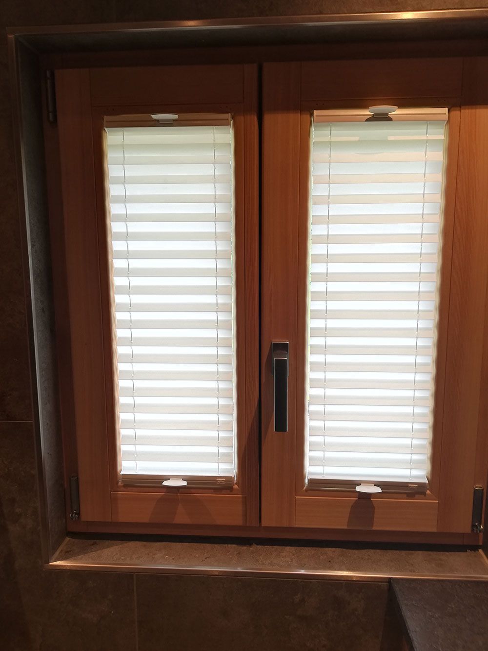 Ein Holzfenster mit weißen Jalousien