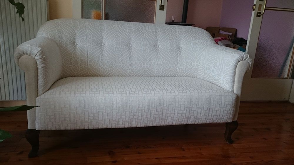 In einem Wohnzimmer steht eine weiße Couch auf einem Holzboden.