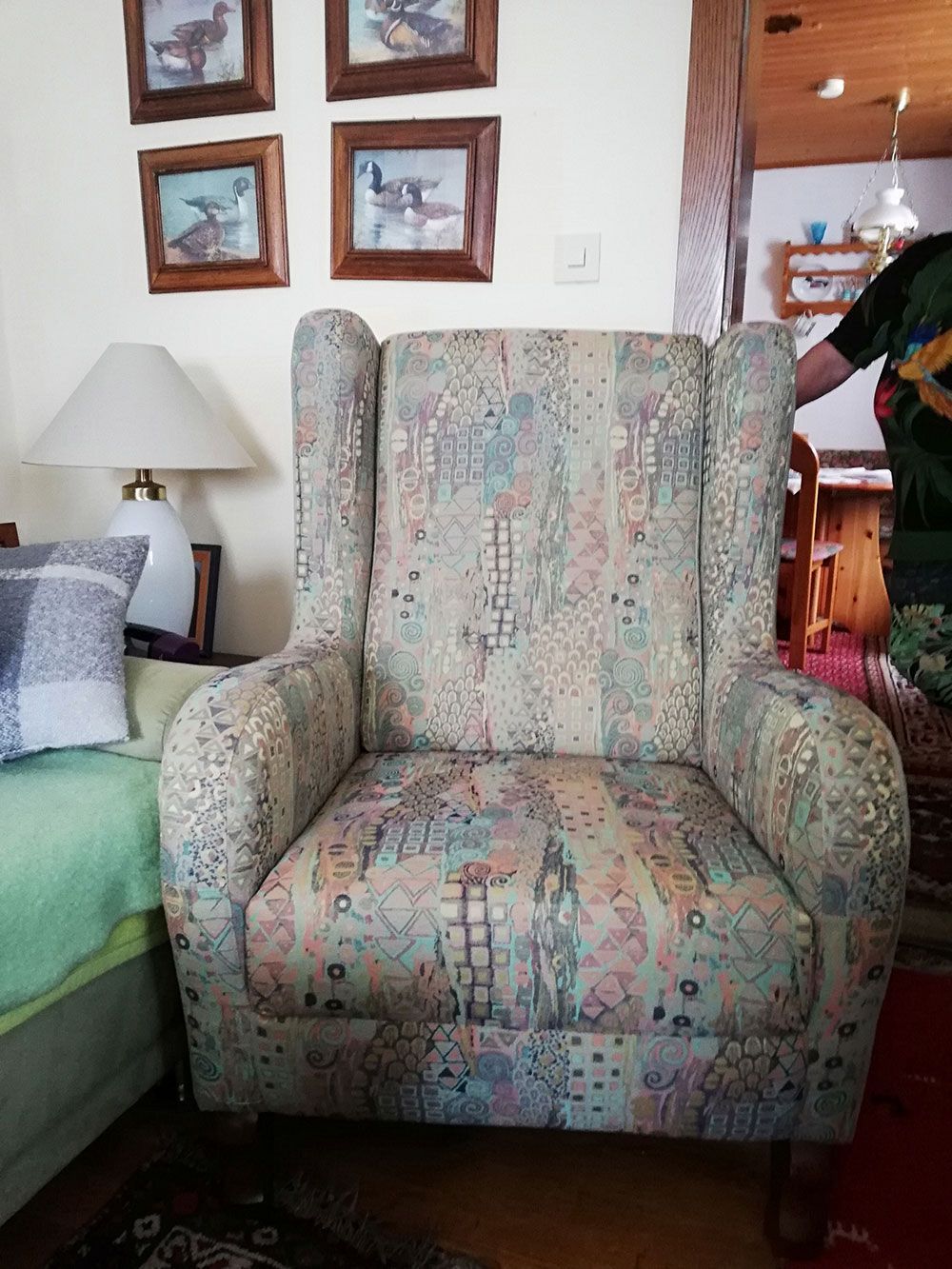 In einem Wohnzimmer steht ein Stuhl neben einem Bett und einer Lampe.