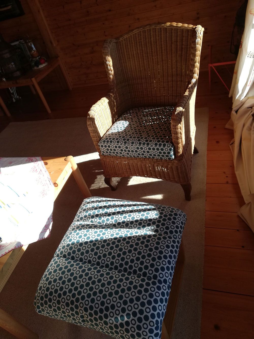 Ein Korbsessel und ein Ottoman in einem Wohnzimmer