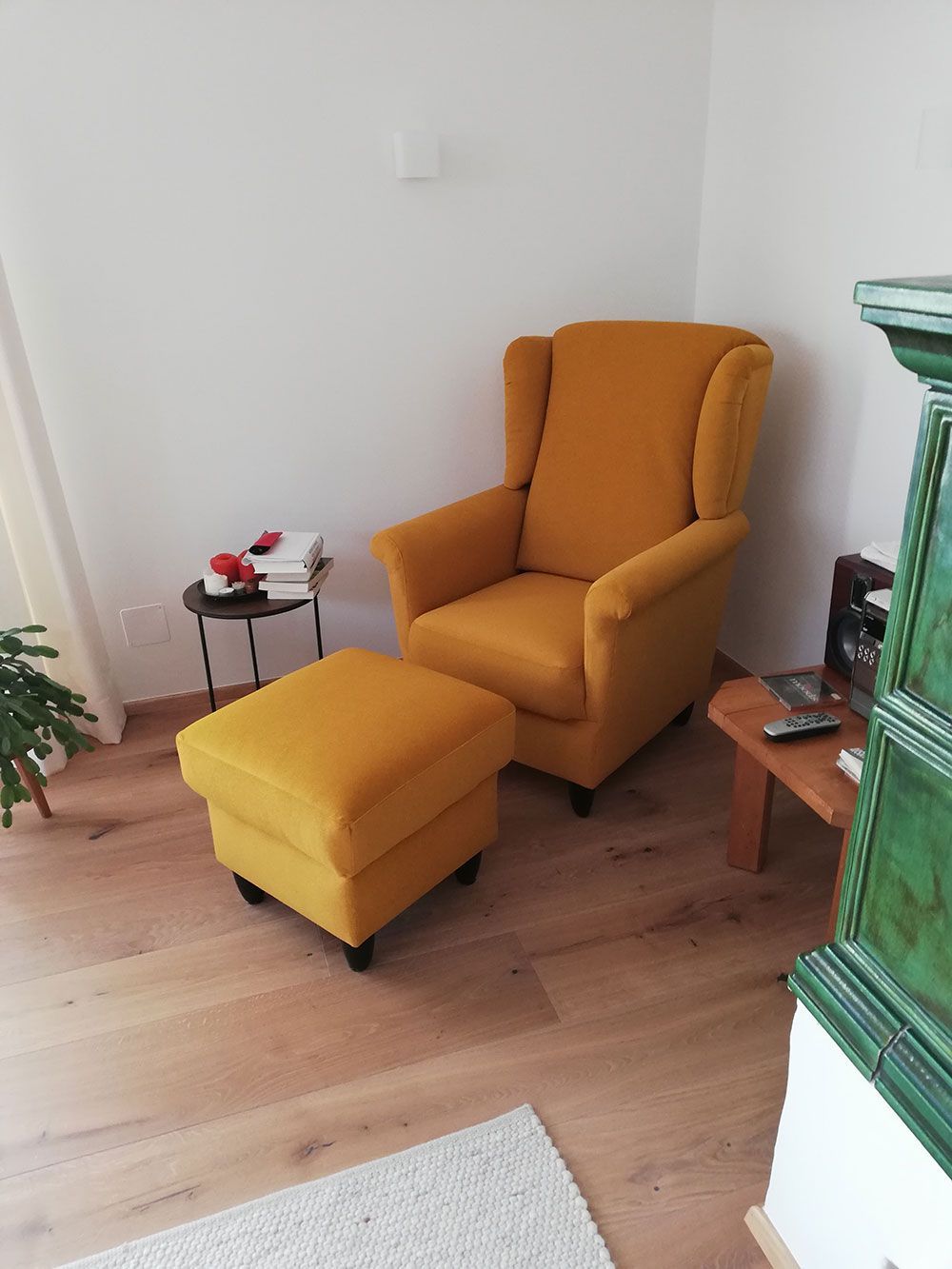 Ein gelber Sessel und ein Ottomane stehen in einem Wohnzimmer.