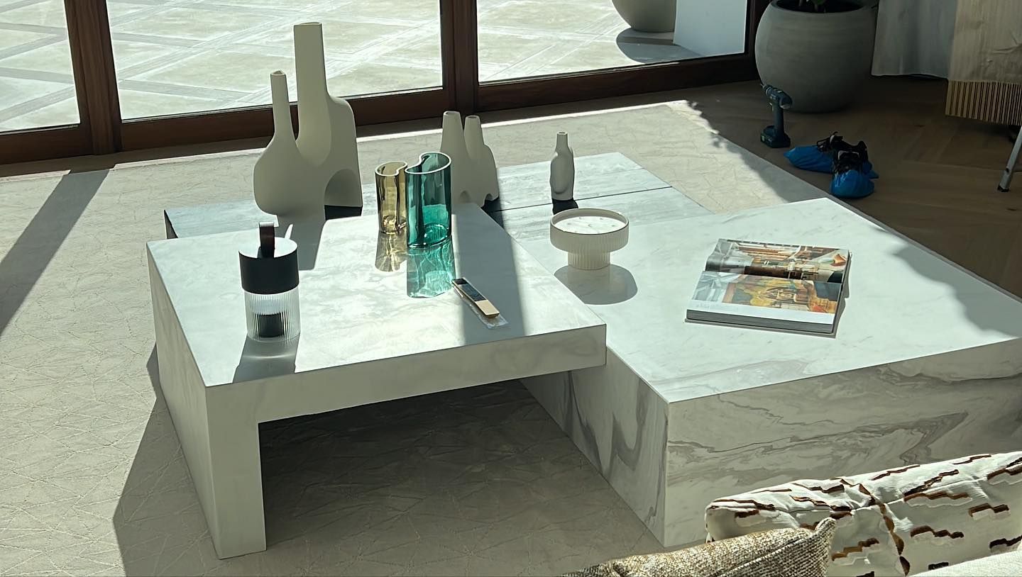 Una mesa de café blanca con jarrones y una revista encima.