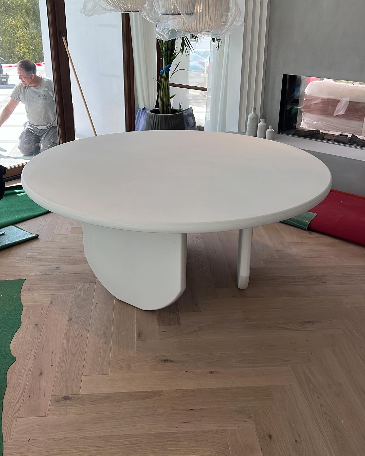 Una mesa redonda blanca está colocada sobre un piso de madera en una sala de estar.