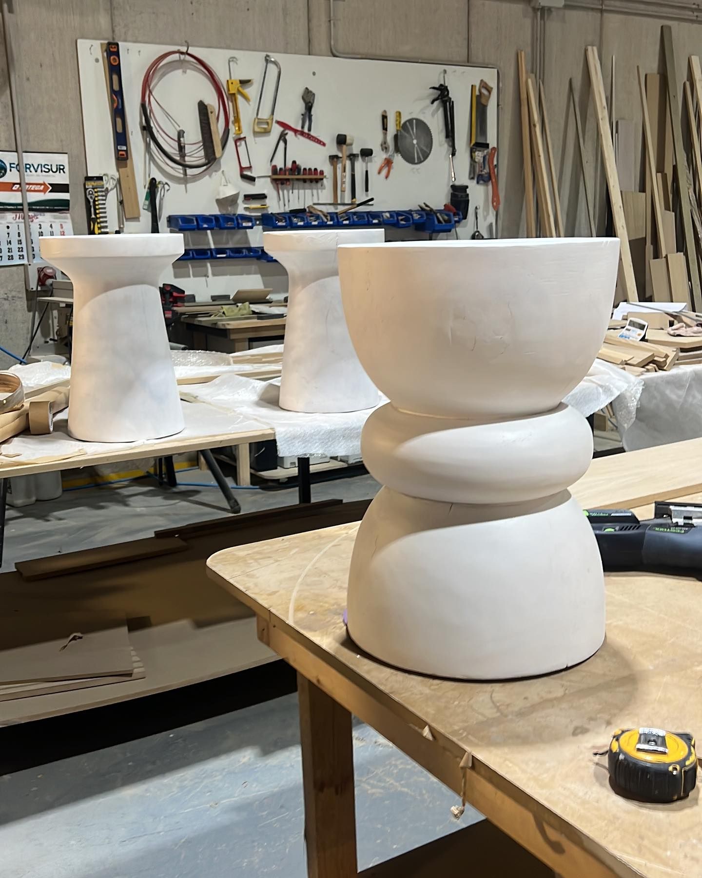 Una cinta métrica se encuentra sobre una mesa de madera en un taller.