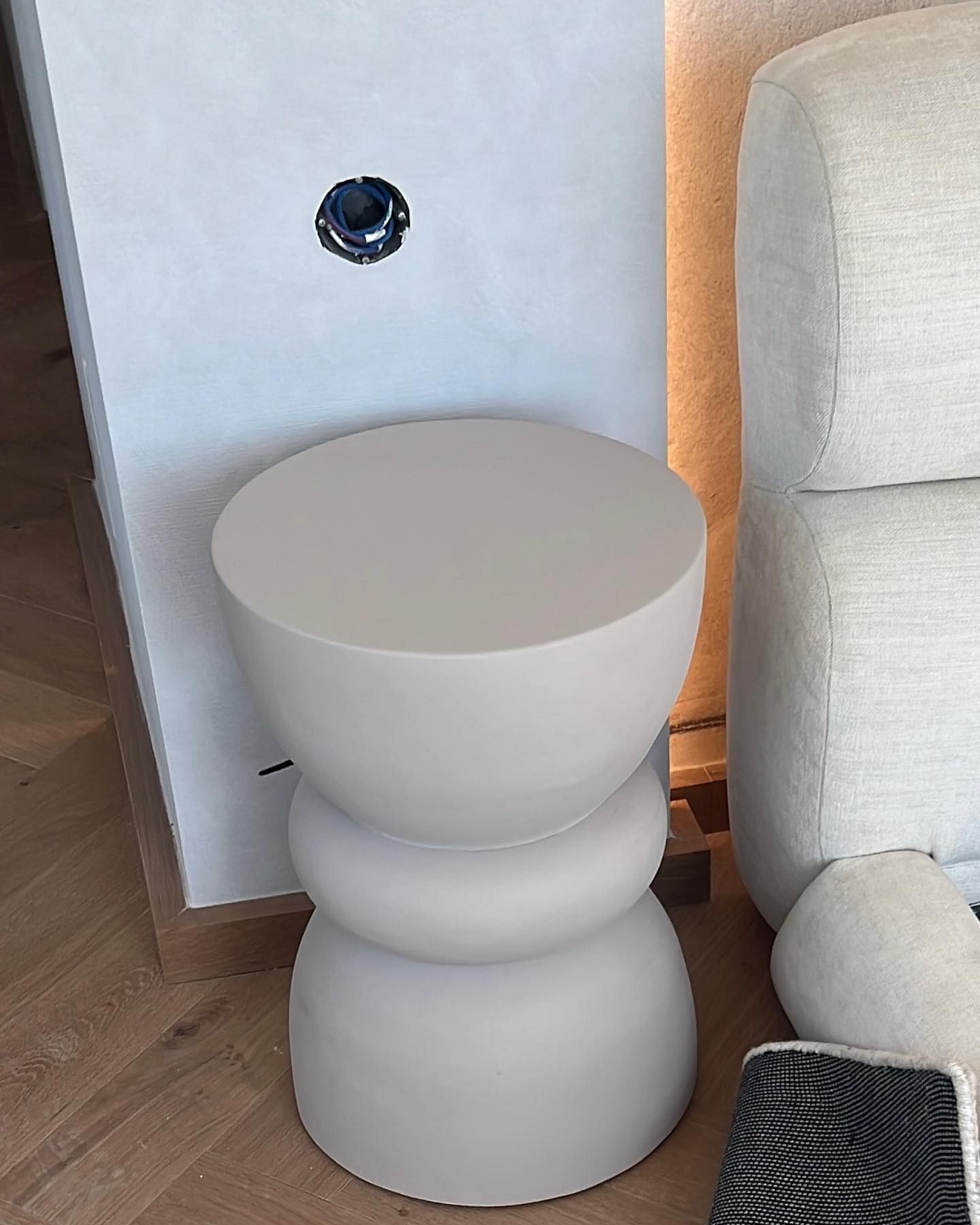 Un taburete blanco está sentado al lado de un sofá blanco en una sala de estar.