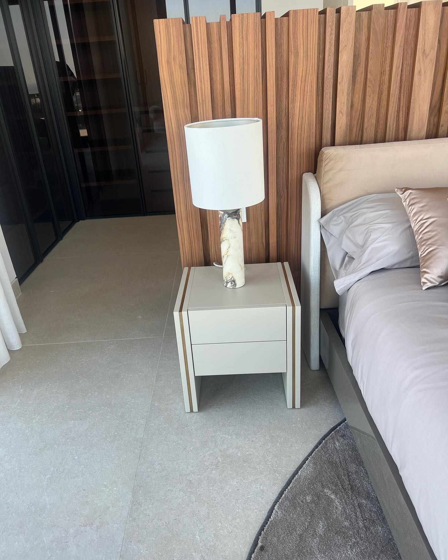 Un dormitorio con una cama y una mesita de noche con una lámpara encima.