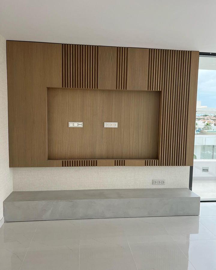 Una sala de estar con una pared de madera y un televisor montado en ella.