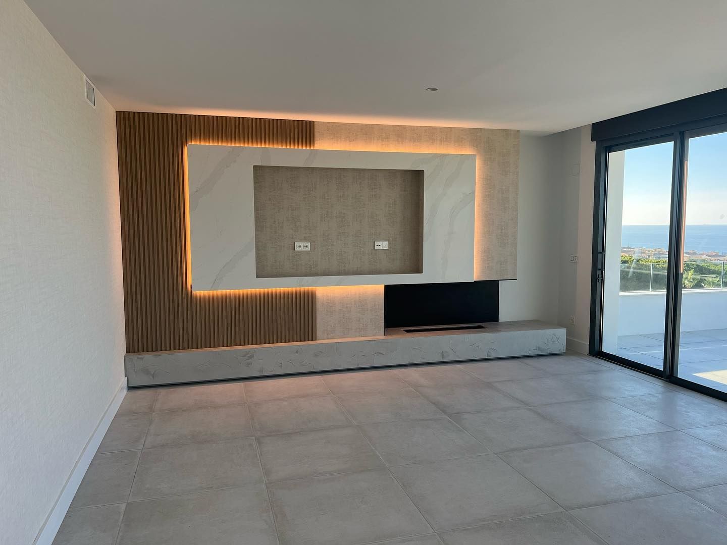 Una sala de estar vacía con un televisor de pantalla plana y una ventana grande.