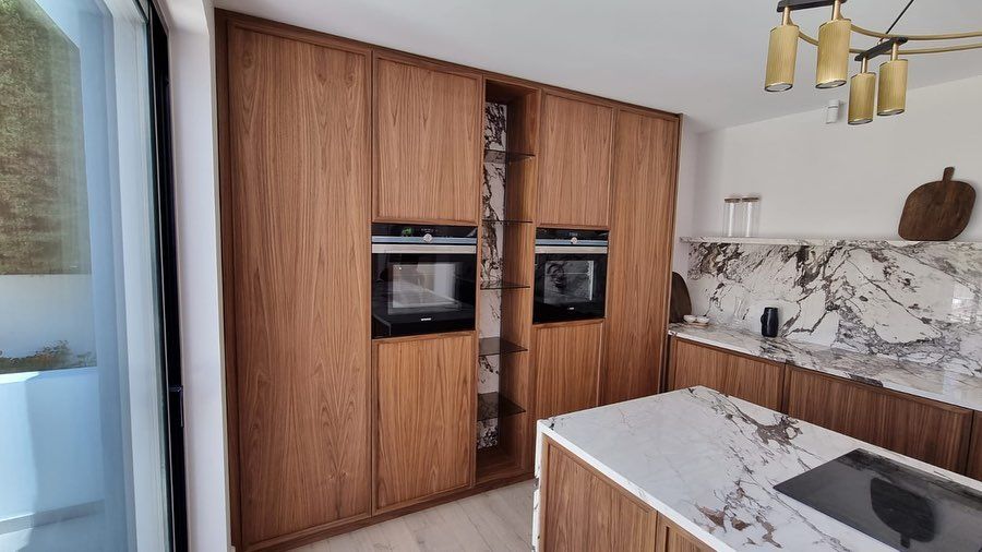 Una cocina con gabinetes de madera y encimeras de mármol.