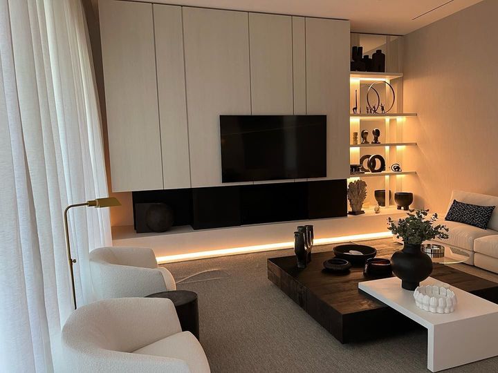 Una sala de estar con sofá, sillas, mesa de café y televisión.