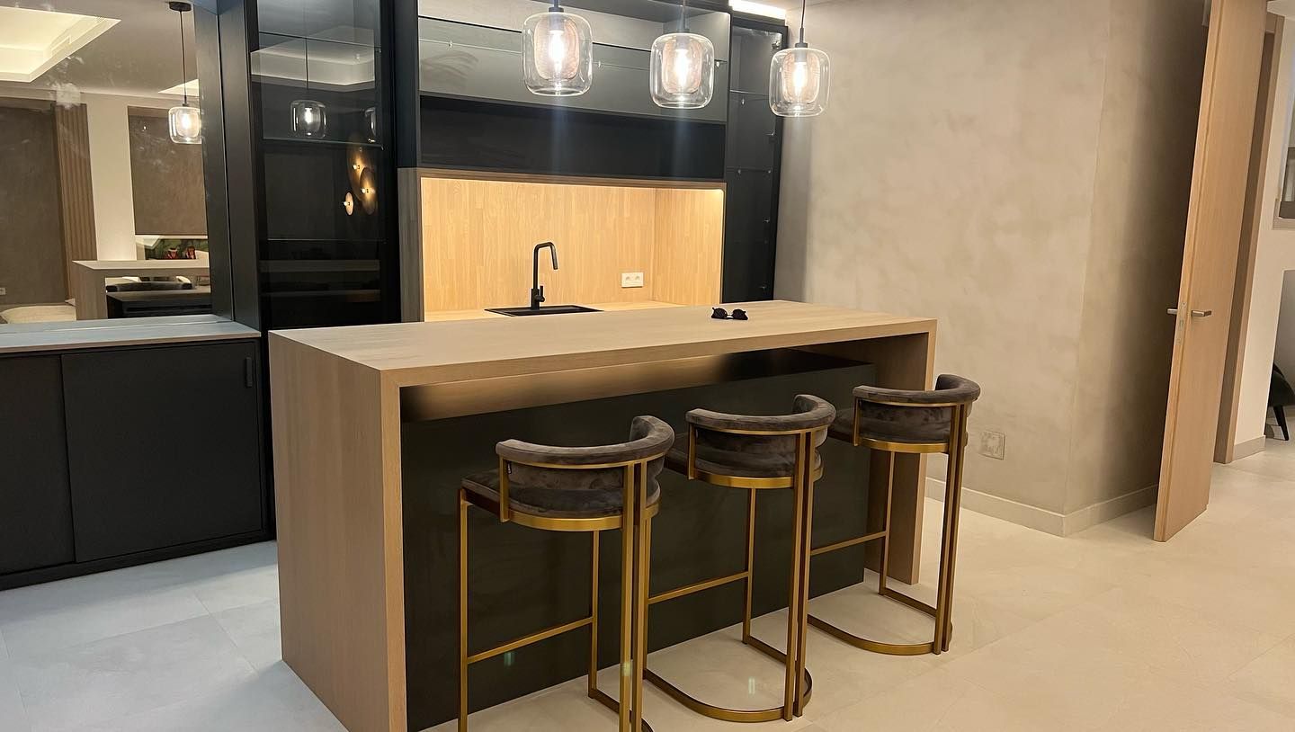 Una cocina con una gran isla y tres taburetes de bar.