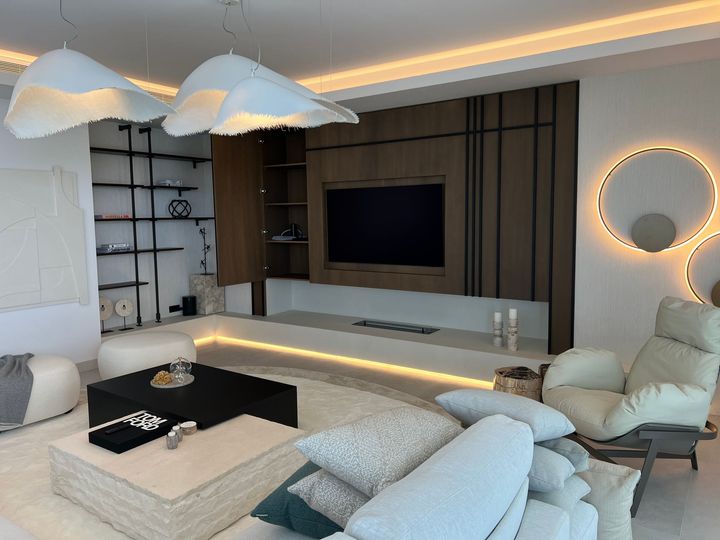 Una sala de estar con sofá, silla, mesa de café y televisión.