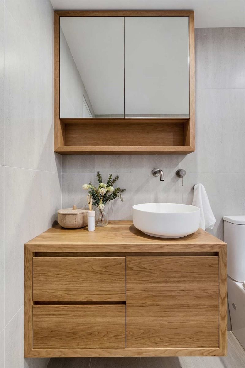 Cocina moderna con gabinetes de madera, isla de mármol, electrodomésticos negros y gran puerta corrediza de vidrio.