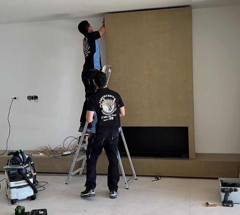 Un hombre en una escalera está trabajando en una pared.