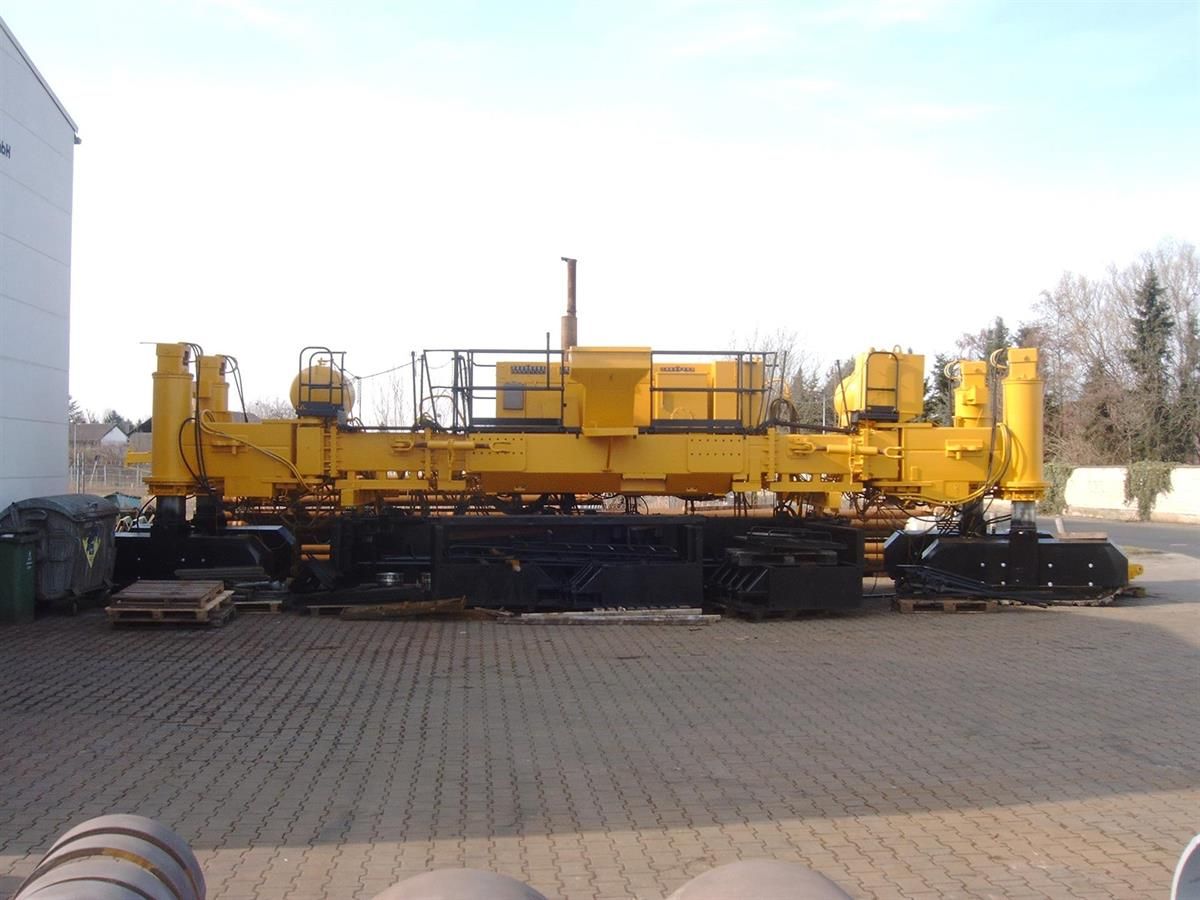 Eine große gelbe Maschine steht auf einem Parkplatz