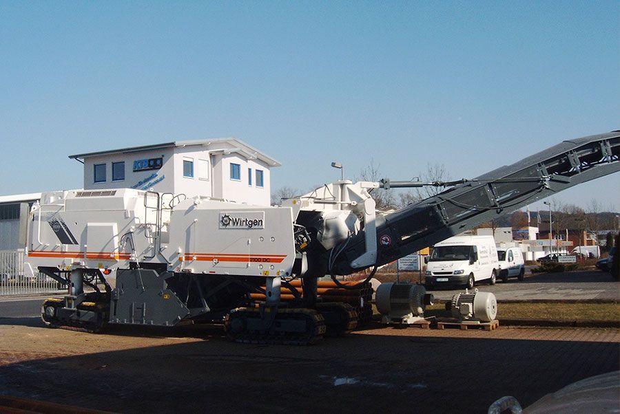 Auf einem Parkplatz vor einem Gebäude steht eine große Maschine.