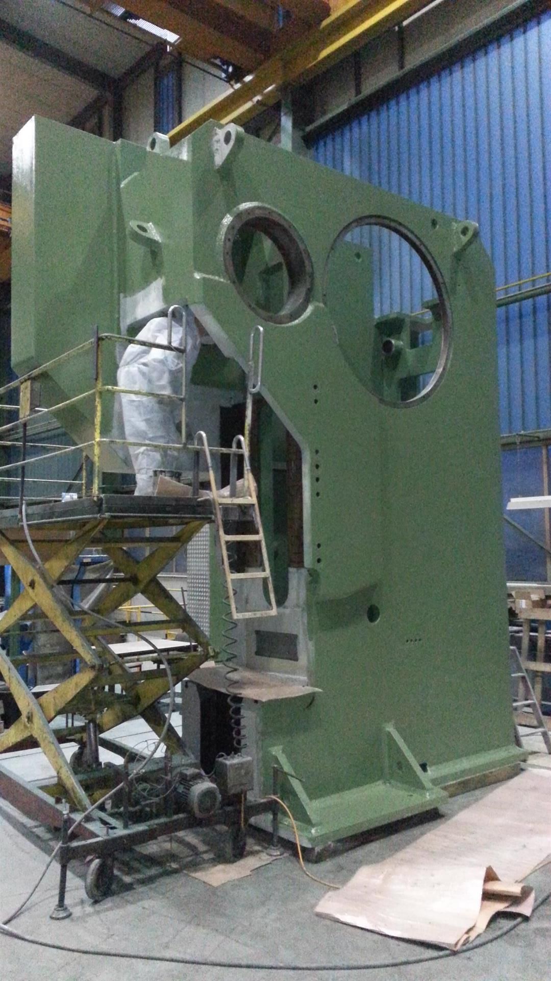 Ein Mann arbeitet in einer Fabrik an einer großen grünen Maschine.
