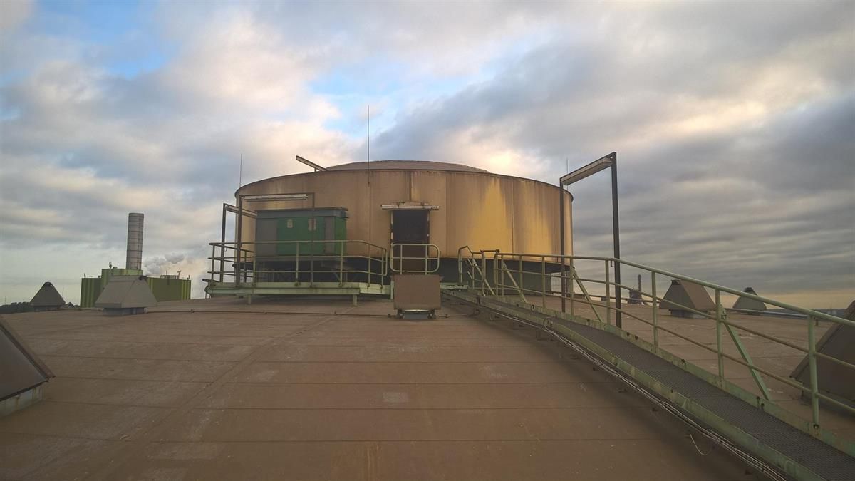 Ein großes Gebäude steht auf einem Dach, im Hintergrund ist ein bewölkter Himmel zu sehen.