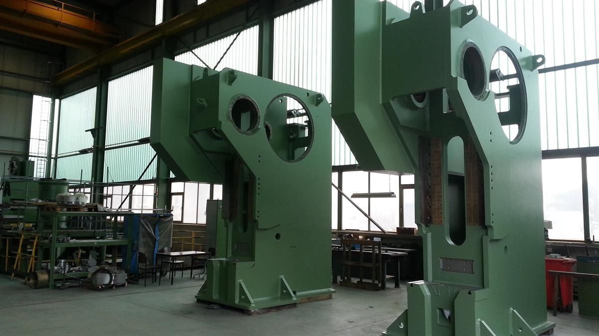 In einer Fabrik steht eine große grüne Maschine.