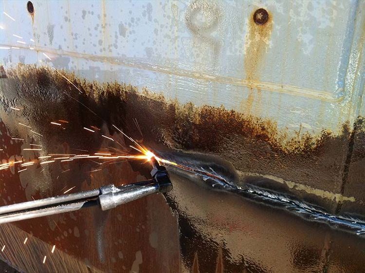 Una persona está cortando un trozo de metal oxidado con un soplete.