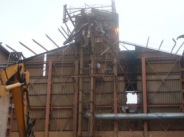 Se está demoliendo un gran edificio con una grúa en primer plano.