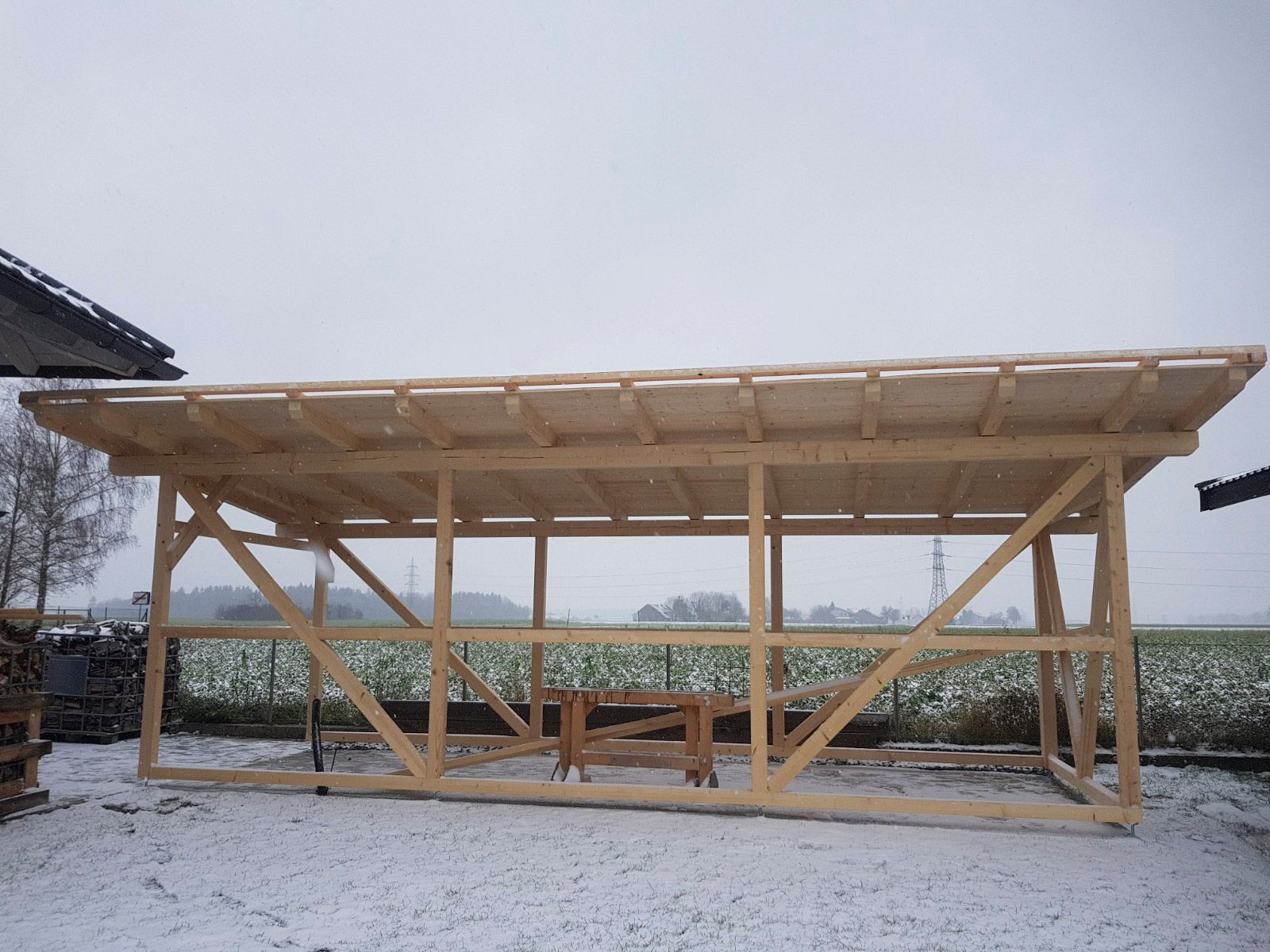 In einem schneebedeckten Feld wird ein hölzernes Schutzgerüst errichtet.