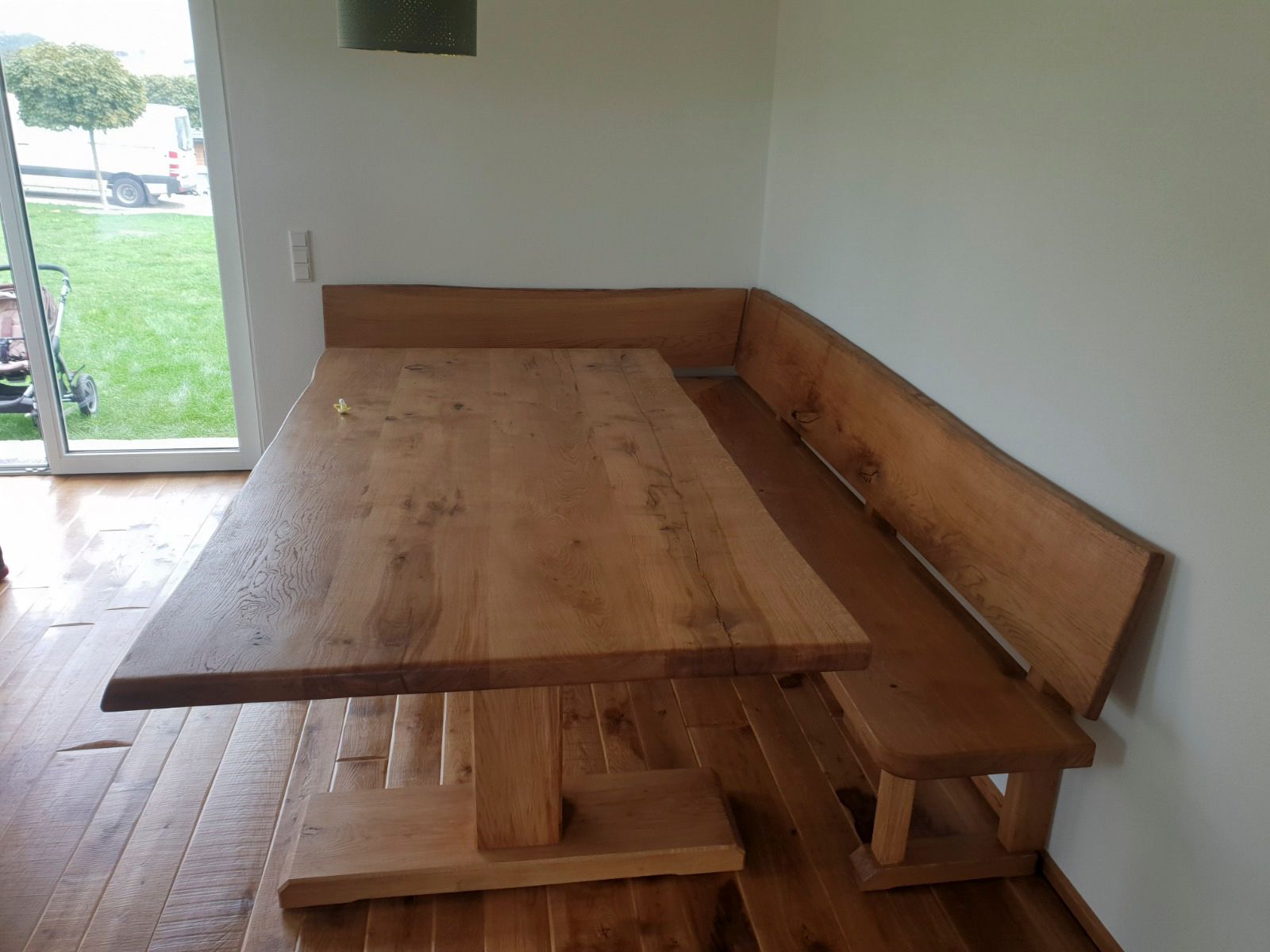 Ein Holztisch und eine Eckbank in einem Zimmer mit hellen Wänden und einem Fenster.