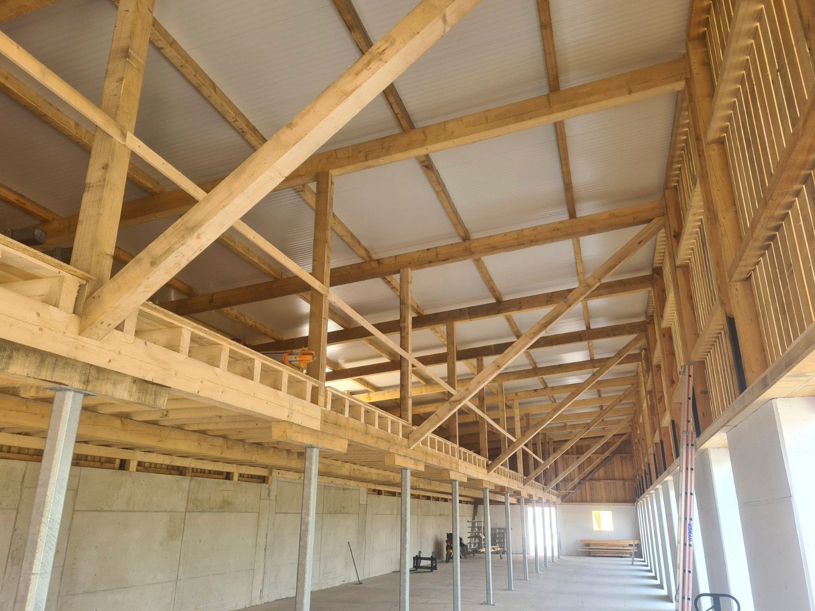 Innenansicht einer im Bau befindlichen Holzkonstruktion mit Zwischengeschoss.