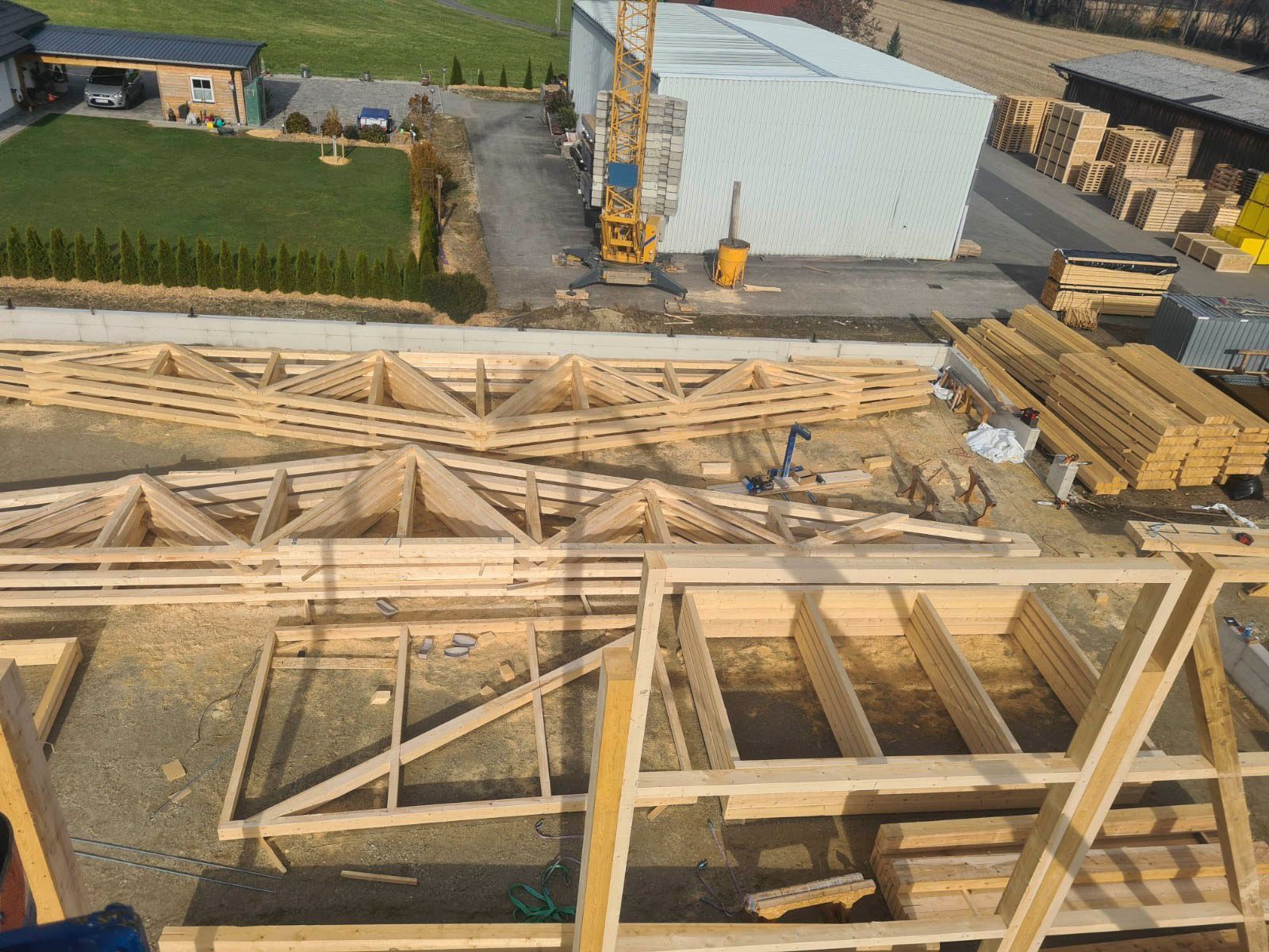 Baustelle aus der Luft: Holzfachwerk und -balken, Kran, im Bau befindliches Gebäude.