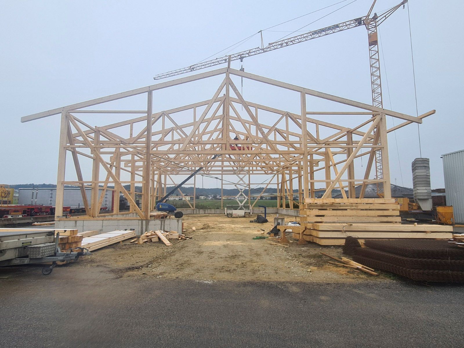 Holzgerüst eines im Bau befindlichen Gebäudes, über dem ein Kran steht.