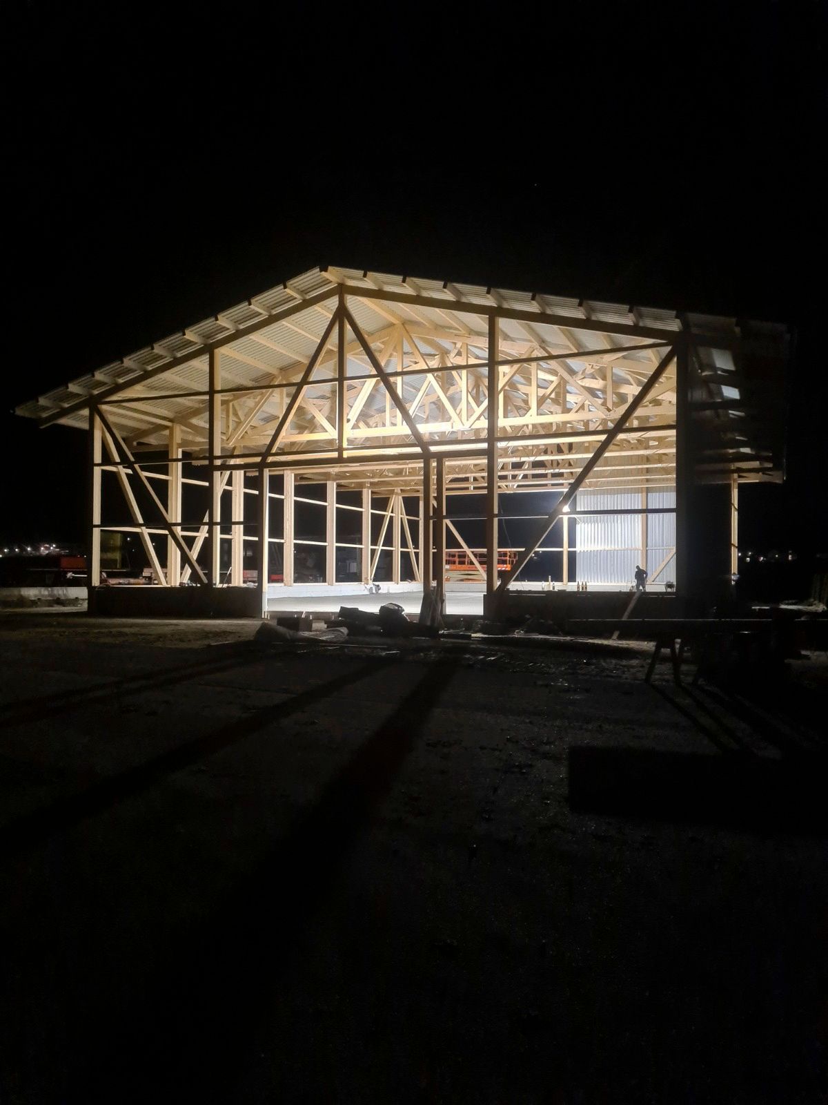 Nachtansicht eines im Bau befindlichen Gebäudes, das Holzgerüst vor dunklem Himmel beleuchtet.
