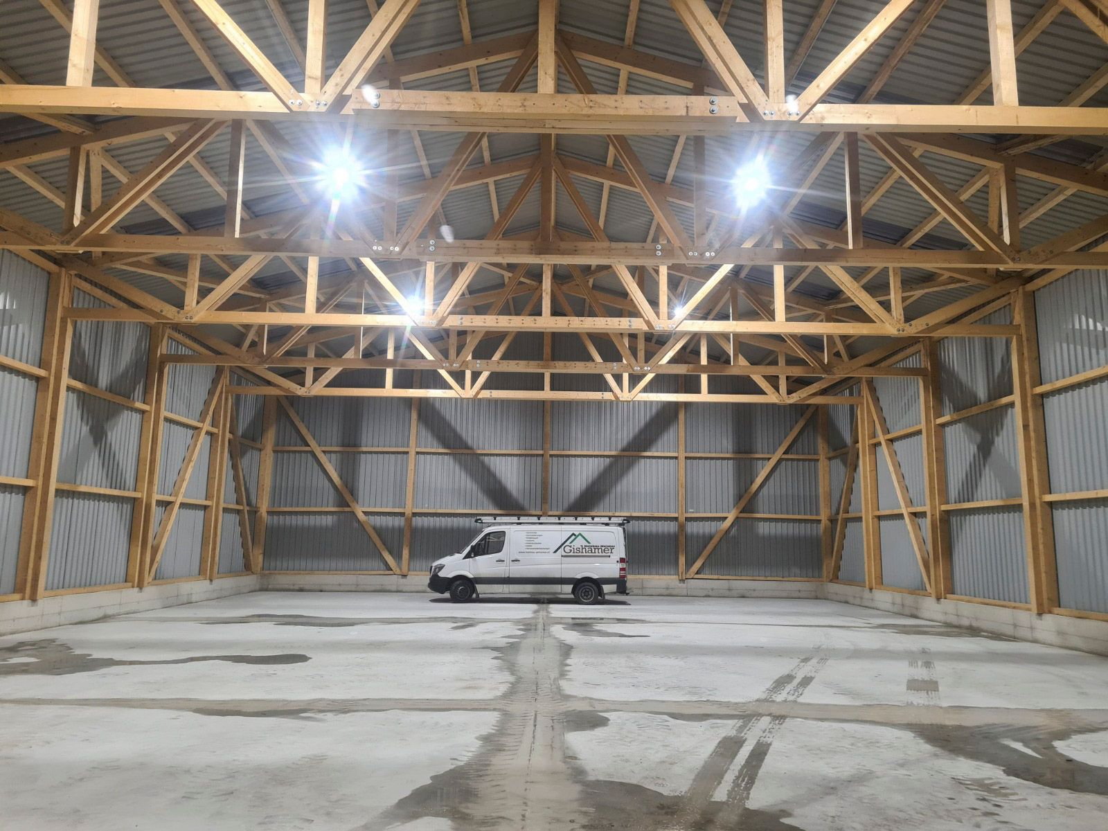 Innenansicht einer großen Lagerhalle in Holzrahmenbauweise mit einem darin geparkten Lieferwagen