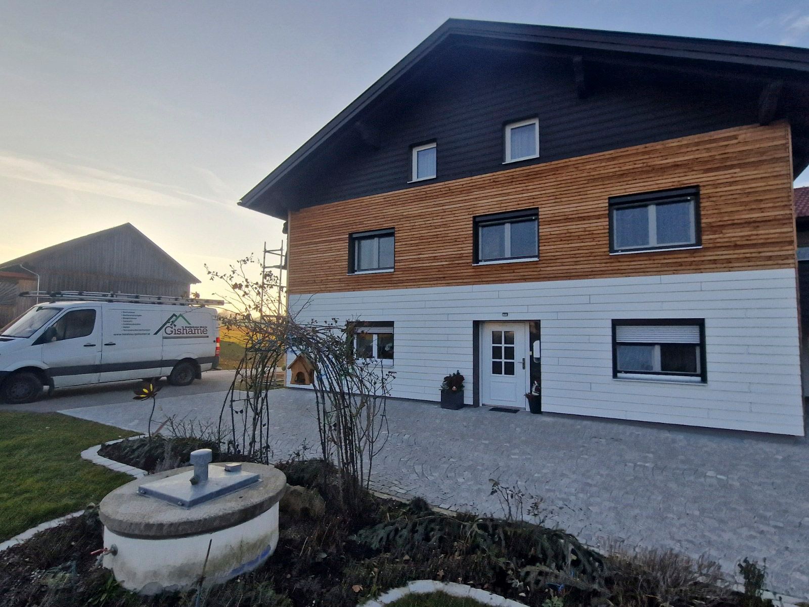 Zweistöckiges Haus mit weißer, holzgetönter und schwarzer Fassade.