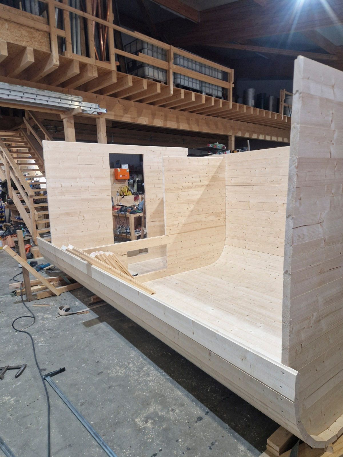 Eine im Bau befindliche Holzkonstruktion, möglicherweise ein Boot oder ein architektonisches Element, in einer Werkstatt.