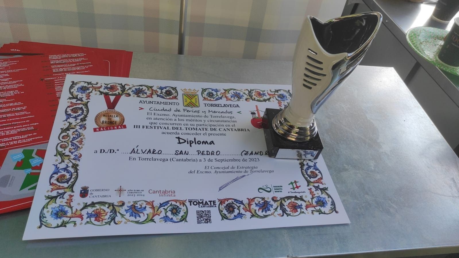 Un trofeo se encuentra en una mesa junto a un diploma.
