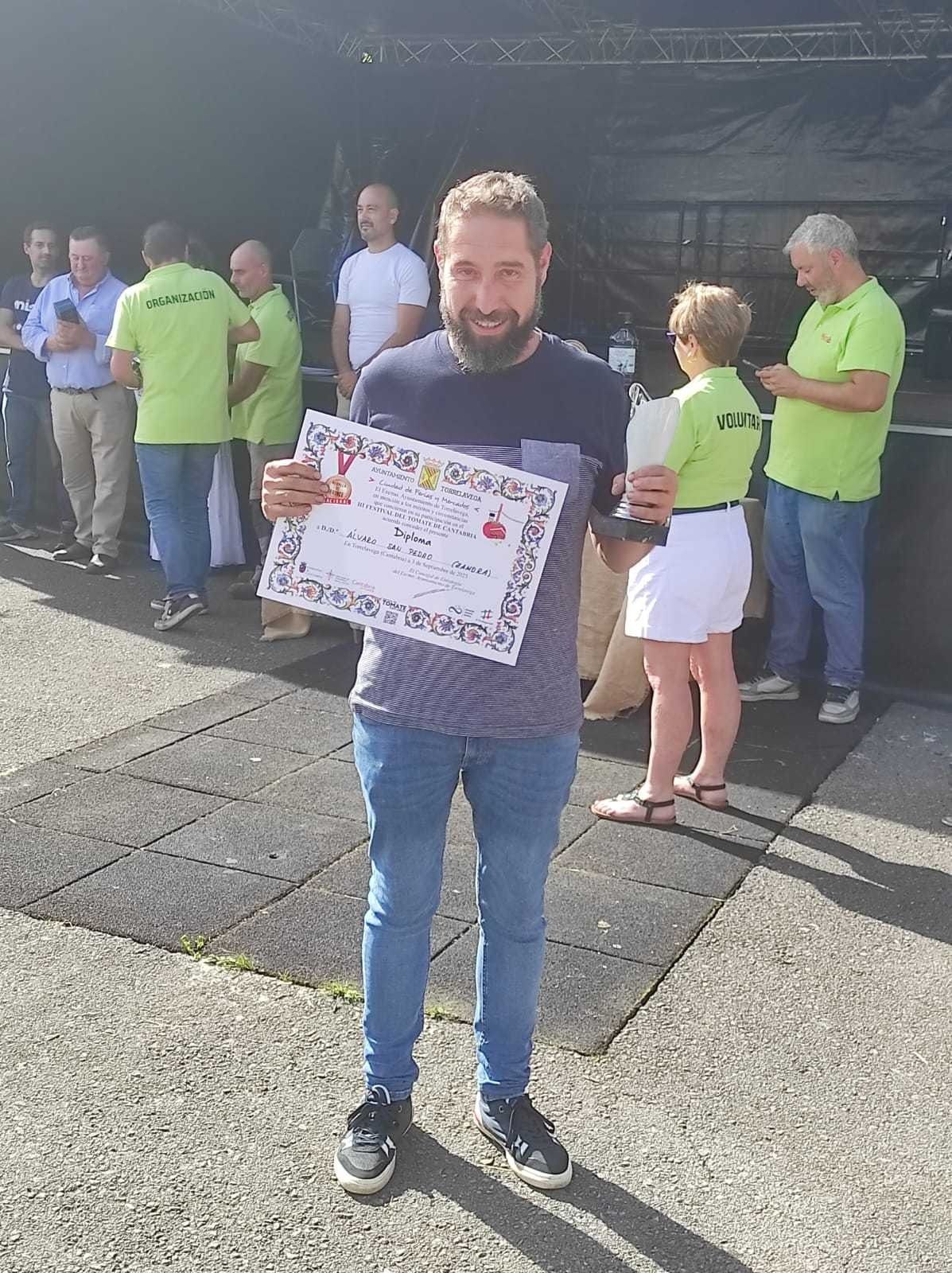Un hombre con barba sostiene un certificado delante de un grupo de personas.