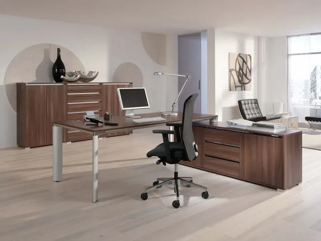 Ein Schreibtisch mit einem Computer und einem Stuhl in einem Büro