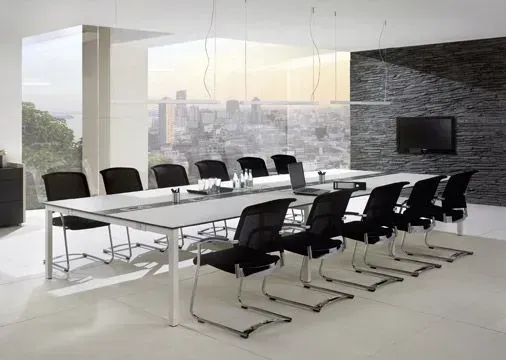 Ein Konferenzraum mit einem langen Tisch und schwarzen Stühlen.