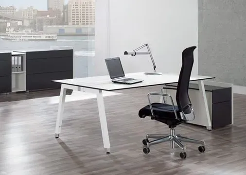 Ein weißer Schreibtisch mit einem schwarzen Stuhl und einem Laptop darauf.