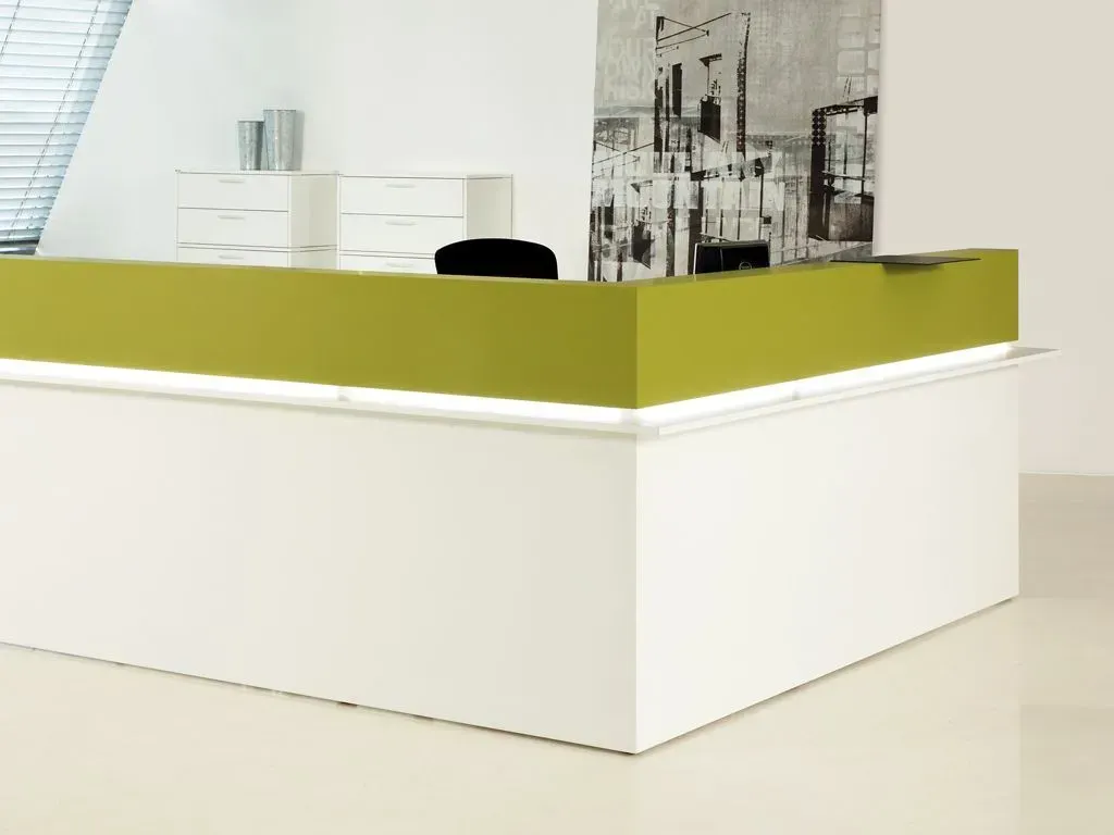 Ein weiß-grüner Rezeptionstresen mit einem Bild an der Wand dahinter