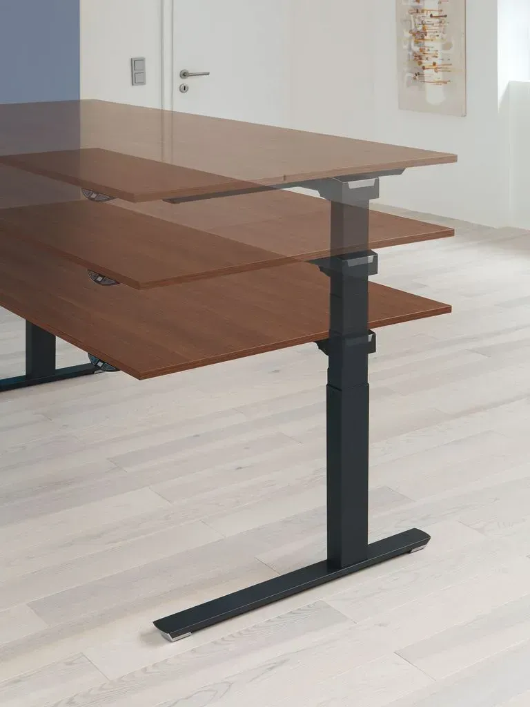 Ein Stehpult mit Holzplatte und schwarzem Untergestell in einem Raum.